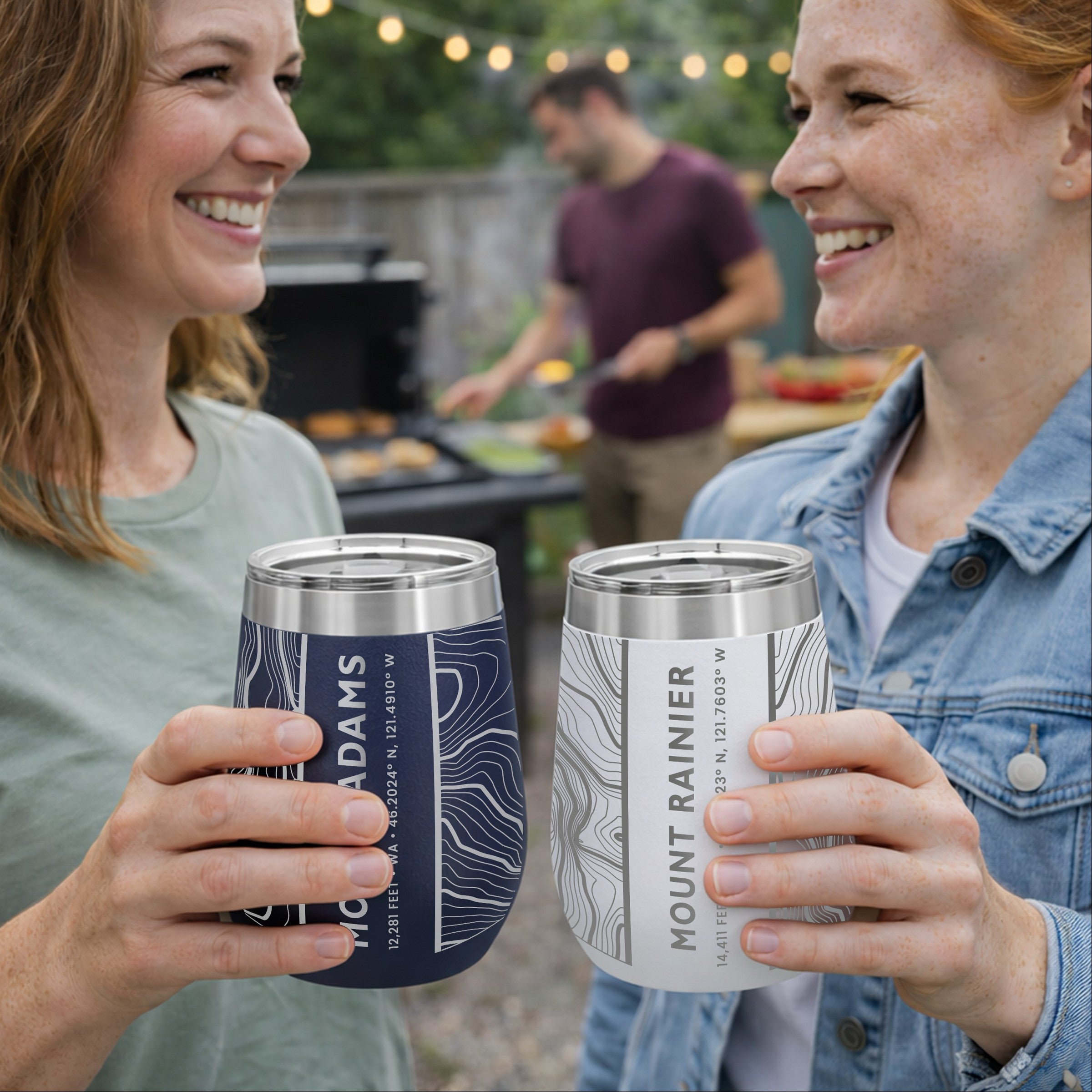 Two friends holding topographic map wine tumblers at a bbq.